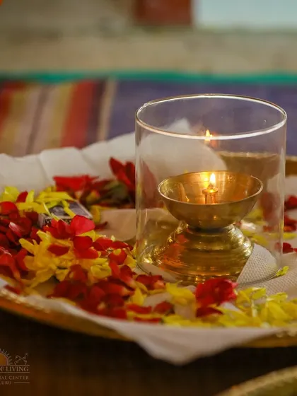 A lit diya (lamp) on a tray of offerings during the Rama Tarak Homa. The lamp symbolizes the light of knowledge dispelling the darkness of ignorance, a central theme of all our celebrations.