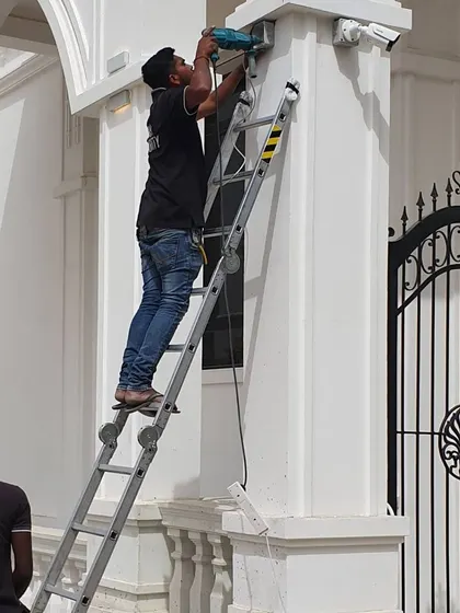 My team working together on a villa project. One person installs the camera while another assists from the ground, ensuring a safe and efficient job.