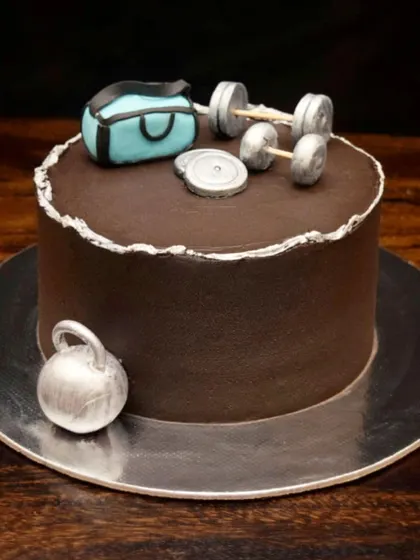 The perfect cheat day cake for a fitness lover. This chocolate cake is decorated with a fondant gym bag, dumbbells, and a kettlebell, all handcrafted to look like the real thing.