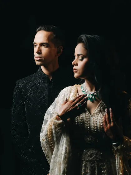 A dramatic, low-key portrait from an engagement ceremony. The focused lighting highlights the couple's elegant attire and serene expressions, creating a timeless, artistic photograph.