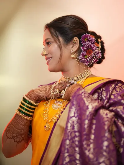 A side profile highlighting a beautiful floral bun using purple and red flowers, which perfectly complements the bride's saree.