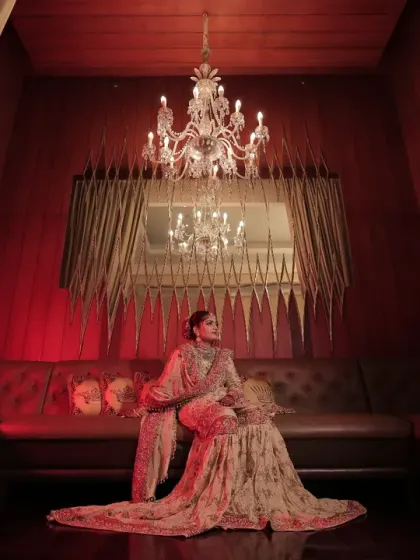 Crafting cinematic moments for our brides is our passion. This portrait, set against a backdrop of dramatic red drapery and a single majestic chandelier, showcases how we use decor to create regal, magazine-worthy photographs.