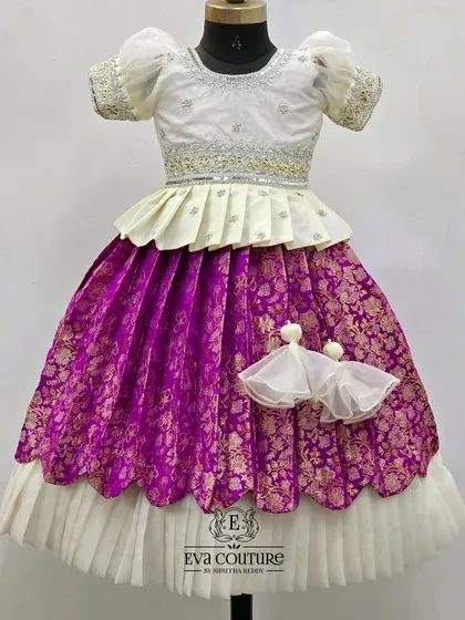A single view of the white and purple Banarasi lehenga set for sisters. The design includes a double-layered skirt with a scalloped hem and delicate tassels, making it a favorite for special occasions.