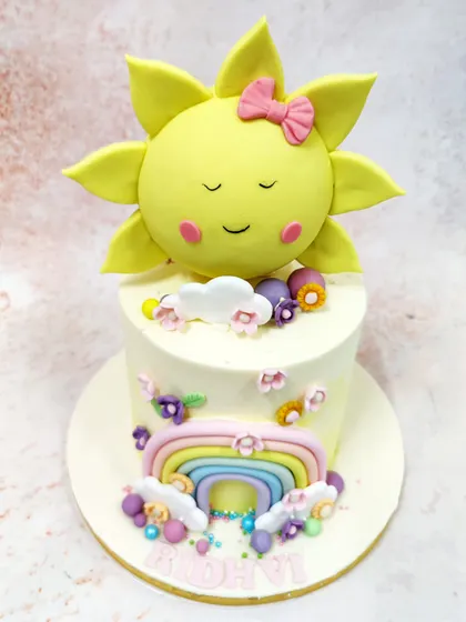 Another view of the sun and rainbow cake, showing the scattered flowers and colorful bead details.