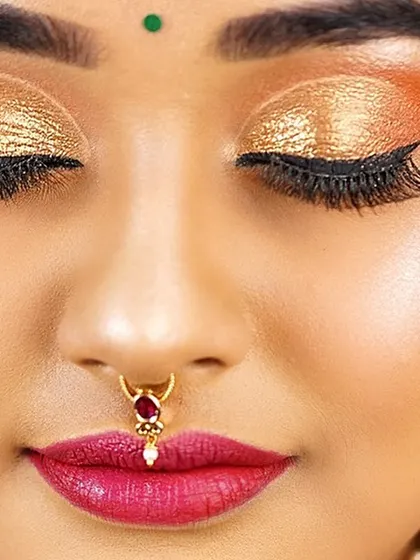 A macro shot of the eye and nose. This shows the precision of the golden glitter eyeshadow, the winged liner, and the traditional nose ring.