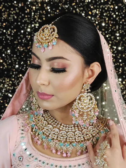 A beautiful pastel look featuring a heavy Kundan necklace with light pink and blue beads. This set is perfect for a daytime wedding or a bride who wants a softer color palette.