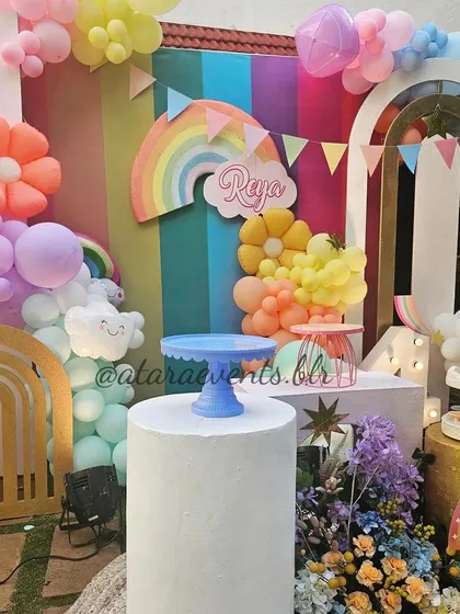 Another view of the vibrant rainbow-themed birthday setup. This shot highlights the cake stands and the '4' marquee light, ready for the celebration's sweet treats.