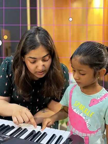 A close-up of a teacher guiding a young student's hands on the piano keys. These moments of personalized instruction are key to building confidence.