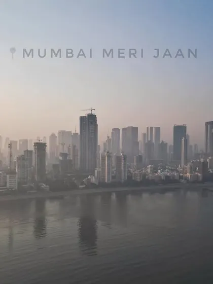 A hazy morning view of the Mumbai skyline from across the water. This shot captures the atmospheric conditions of the city, with the silhouettes of skyscrapers creating a moody and evocative cityscape.