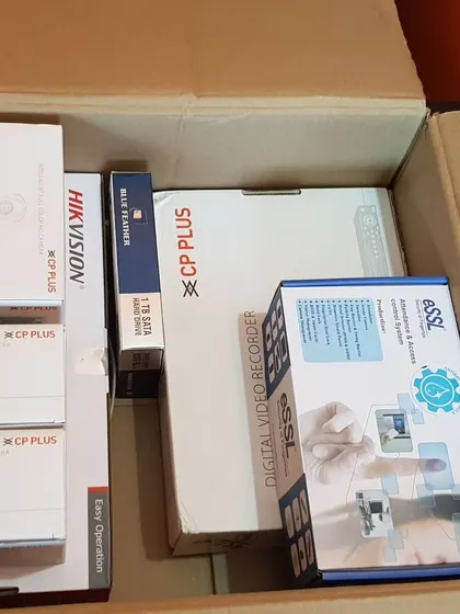 A box of mixed security equipment for a comprehensive installation, including a CP Plus DVR, an eSSL biometric system, and a Hikvision video door phone.