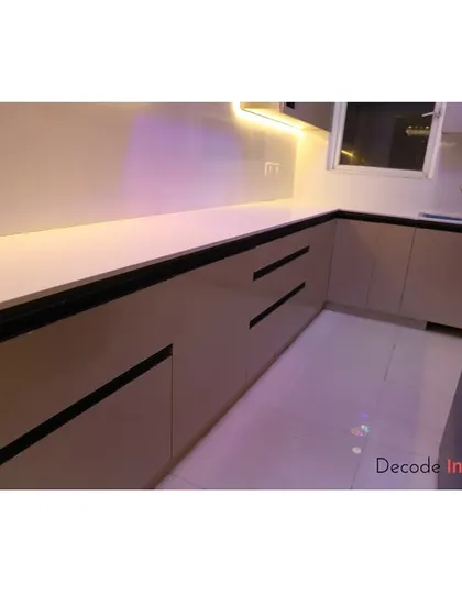 A wider angle of the minimalist kitchen, showing the L-shaped layout and the effective use of under-cabinet lighting.
