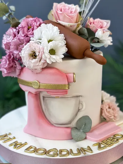 The perfect cake for a baker! This design features a miniature pink stand mixer, a rolling pin, and a whisk, all made from sugar.