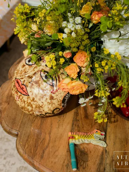 A quirky detail from the 'Kesar Sehar' Haldi, where a hand-painted Indian mask becomes a unique vase. These details add personality and a sense of discovery to the event.
