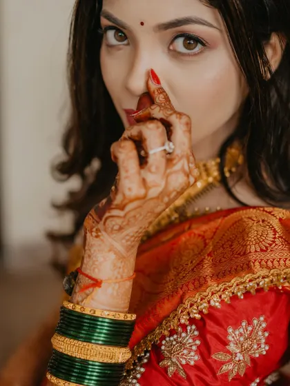 A playful and artistic close-up. This shot focuses on the bride's expressive eyes, flawless makeup, and intricate henna design.