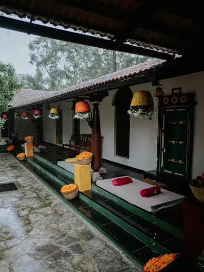 The venue's traditional courtyard during a rain shower, with colorful decor elements like hanging baskets and floor seating adding vibrancy to the moody atmosphere.