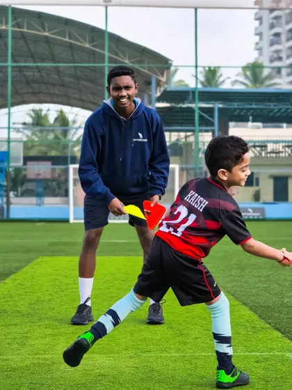 We use different tools to make training engaging. Here, a coach uses a paddle to guide a young player through an agility drill.