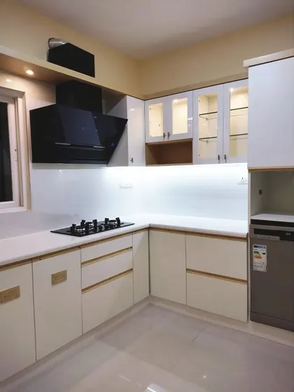 Another view of the minimalist white and pine kitchen, showing the integrated dishwasher and the clean lines of the handleless cabinetry. The glass-fronted overhead cabinets add a touch of lightness.