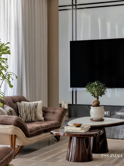 Simplicity and ethereal elegance define this living room corner. The two-tone sofa, nested coffee tables, and a carefully placed bonsai tree create a moment of calm and sophisticated style.