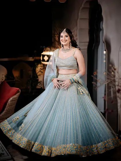 The bride twirls in her powder blue lehenga, showcasing its beautiful flare and the way it catches the light, a perfect choice for an evening of celebration.