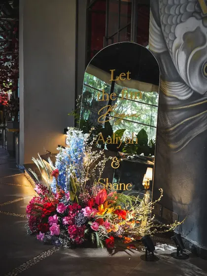 A personalized mirror sign welcomes guests to Aaliyah and Shane's Mehendi. The reflection of the venue in the mirror adds a dynamic and interesting visual element.