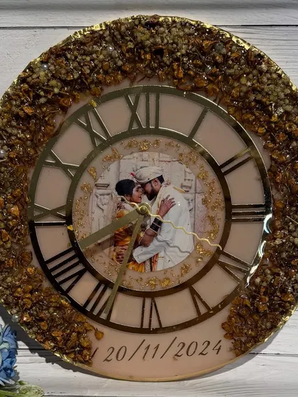 This elegant clock features a photo of the couple in the center, surrounded by a classic clock face and a border of preserved golden flowers.