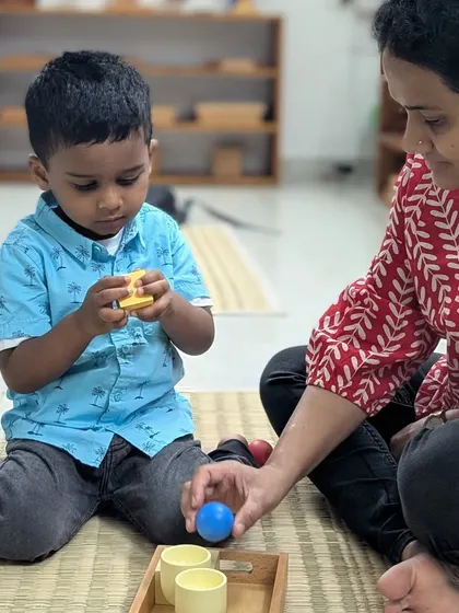 A child explores the texture and shape of different objects with his mother nearby. This gentle introduction to our sensory materials is guided by curiosity and supported by a trusted adult.
