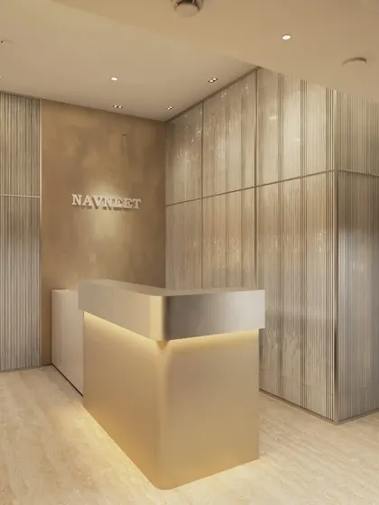 The reception desk for "Navneet" in a vertical campus, featuring an elegantly backlit desk and textured wall panels. The design creates a refined and professional first impression for visitors.