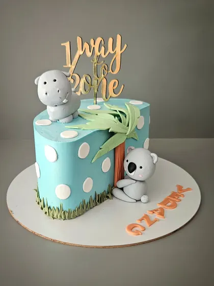 A half birthday cake for Ozean, who is halfway to one! This cake features cute fondant animals like a koala and a hippo, perfect for a 6-month celebration.