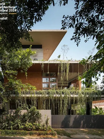 The front facade of the 'House of Greens', where layers of concrete, brick, and cascading plants create a rich, textured elevation that integrates with the streetscape.