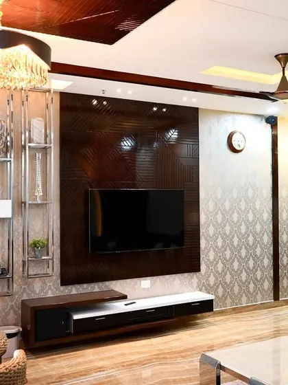 A luxurious living room TV unit featuring a mix of dark wood veneer, stainless steel display shelves, and textured wallpaper. The design is both grand and functional, providing ample storage and display space.