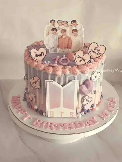 A special cake for a BTS fan. This design features the band's logo, pictures of the members, and lots of hearts in their signature purple and pink colors.