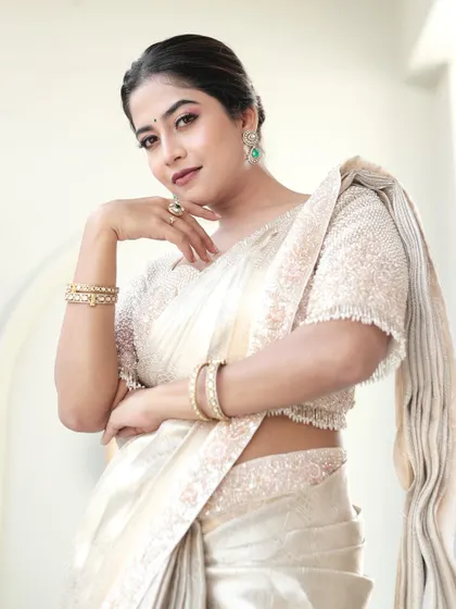 A portrait shot highlighting the beautiful pearl work on the blouse and the subtle sheen of the tissue silk saree.