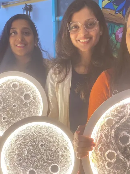 A group of friends proudly showing off the moon lamps they made together in our workshop.