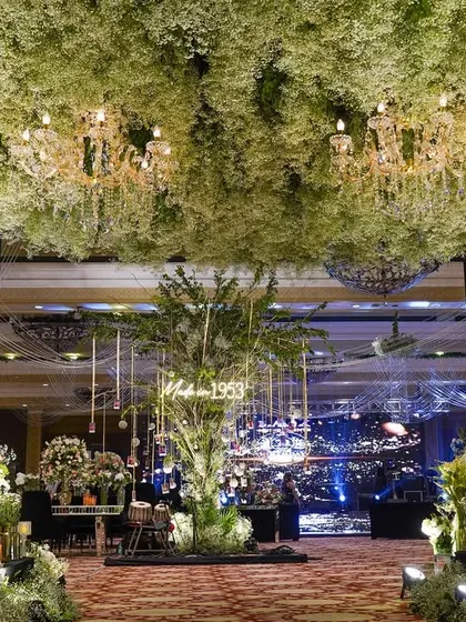 A beautiful entrance to a 70th birthday celebration, featuring a ceiling of baby's breath that looks like a soft cloud. The entire space was designed with white florals and elegant lighting to mark the special milestone.