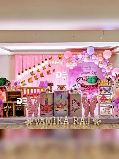 A unicorn and butterfly themed party for Vamika Raj. This setup combines two popular magical themes with a pink and purple color scheme, a castle prop, and themed pedestals.