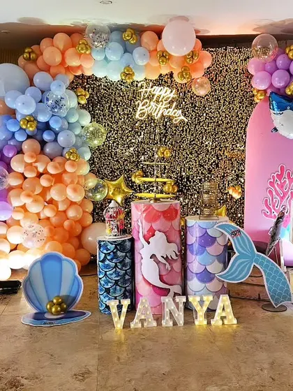 A magical mermaid-themed 5th birthday party for Vanya. The decor is filled with details like a sequin backdrop, character cutouts of Ariel, balloon arrangements in ocean colors, and light-up letters, creating an enchanting underwater world.