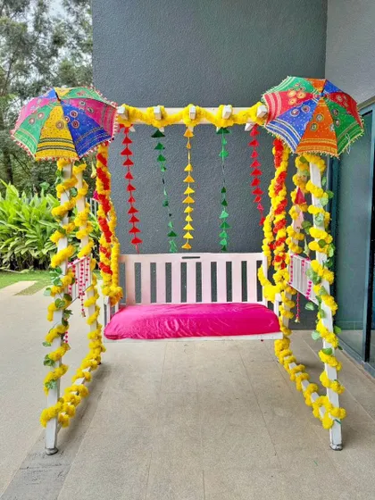 A decorated jhula, or swing, adds a playful and traditional element to festivals like Teej. I adorned this swing with bright yellow marigold garlands and colorful Rajasthani umbrellas for a fun and festive touch.