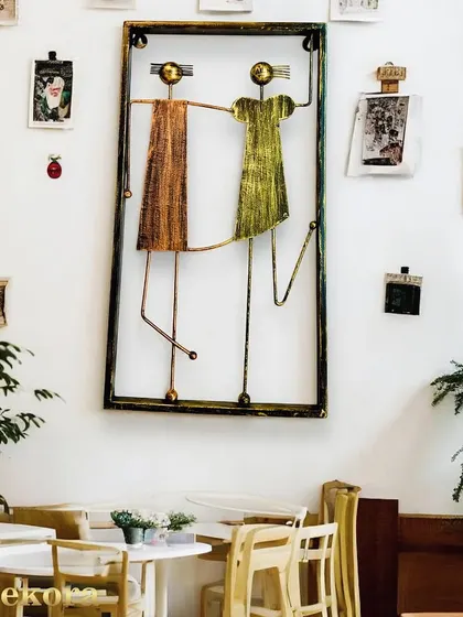 This charming metal wall art features two stylized figures holding hands within a frame. It's a sweet and artistic piece that celebrates connection.