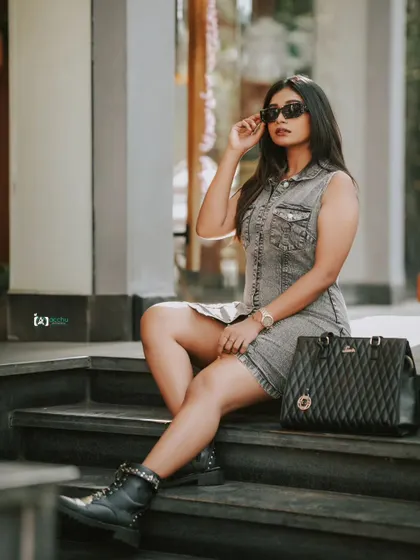 Street style at its best. This shot captures a full look, from the denim dress and combat boots to the sunglasses and handbag, against a simple urban backdrop.