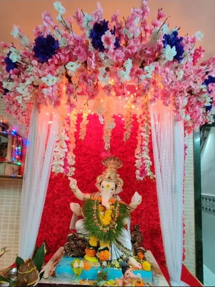 This cherry blossom-themed decor combines pink and white artificial flowers with a red backdrop and fairy lights. It's a vibrant and modern way to welcome Bappa into your home.