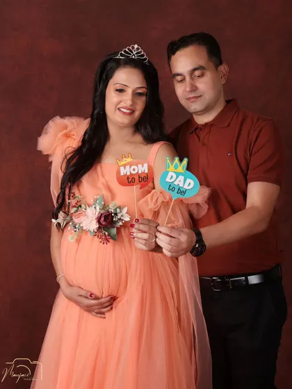 A fun and celebratory portrait. This couple uses props to announce they are becoming a 'Mom' and 'Dad', their smiles lighting up the frame.