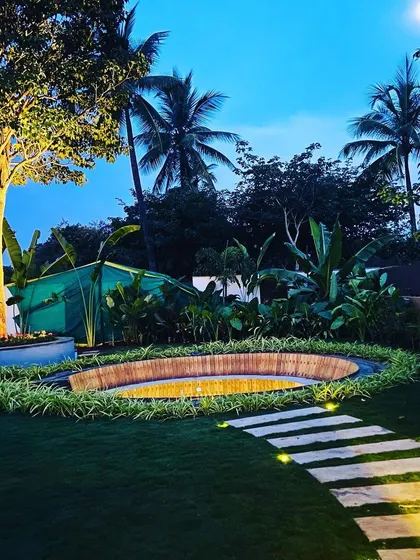 A wider view showing the lit pathway leading towards the sunken lounge, with the illuminated tree as a backdrop.