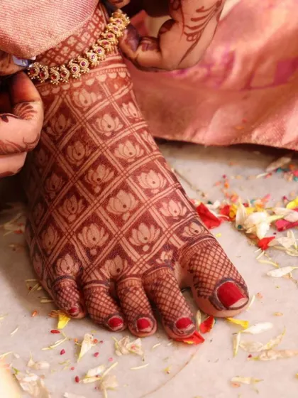 Another shot of the toe-ring ceremony, highlighting the detailed henna work on the bride's foot.