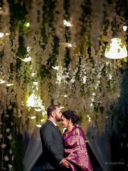 A romantic and intimate moment under a canopy of hanging white flowers and lights.