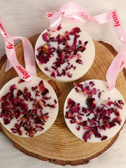Our wax sachets with dried rose petals, displayed on a natural wood slice.