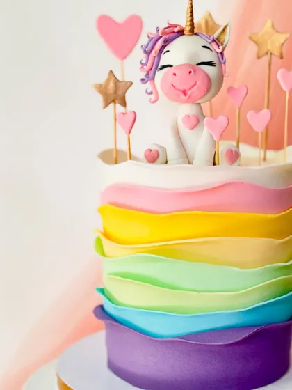 A closer look at the happy unicorn topper and the unique buttercream texture of this rainbow cake.