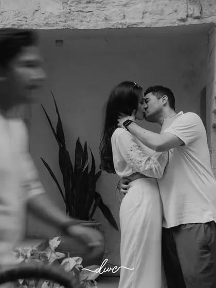 A stolen kiss captured in timeless black and white, with the motion of a passerby adding a dynamic, street-style feel to this pre-wedding photo.