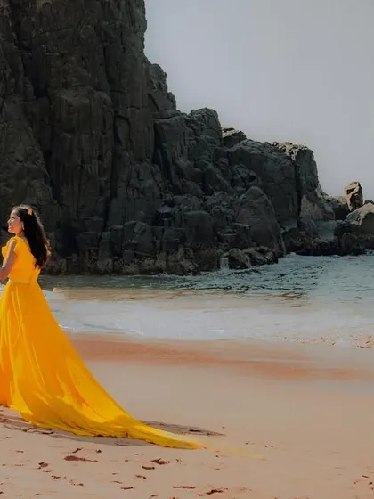 Walking towards forever on a beautiful beach. The long yellow trail of her gown creates a stunning visual against the blue sea, perfect for a destination pre-wedding shoot.