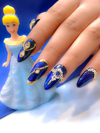 Royal blue nails fit for a queen, inspired by Cinderella for a Navratri look. This design features intricate gold beadwork and sparkling crystal patterns.