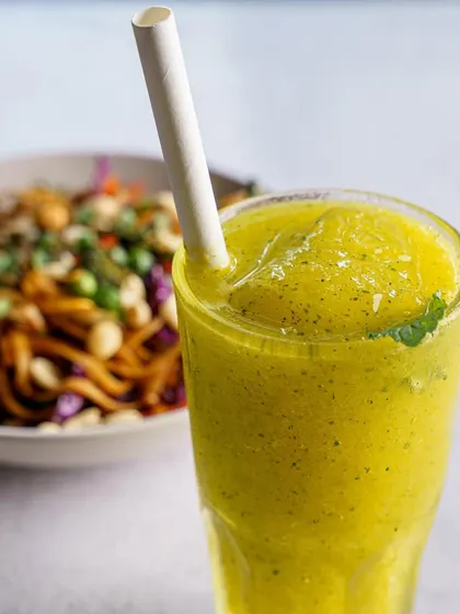 A raw mango drink, styled to look tangy and refreshing. We use context, like the bowl of noodles in the background, to suggest perfect food pairings.